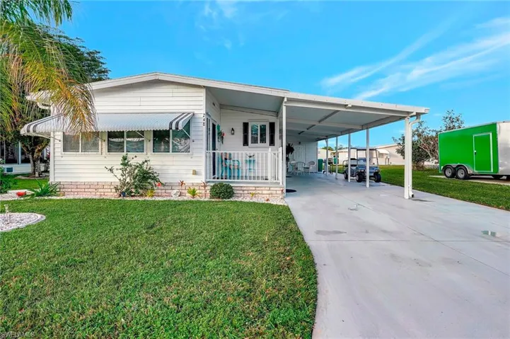 View of front facade featuring a front lawn and a carport