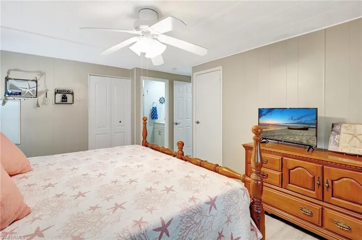 Bedroom with ceiling fan, wood walls, a closet, and ensuite bath