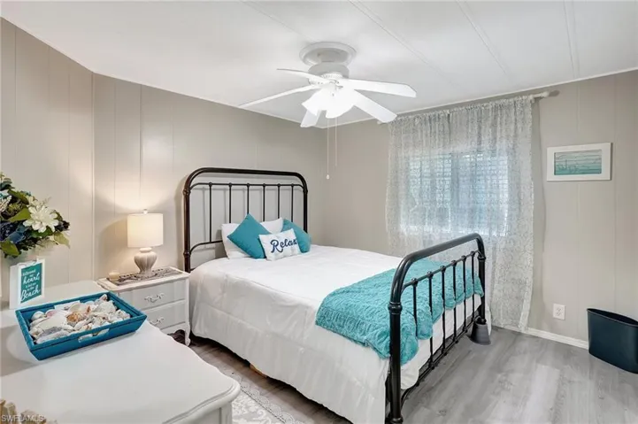 Bedroom featuring ceiling fan, wood walls, and wood-type flooring