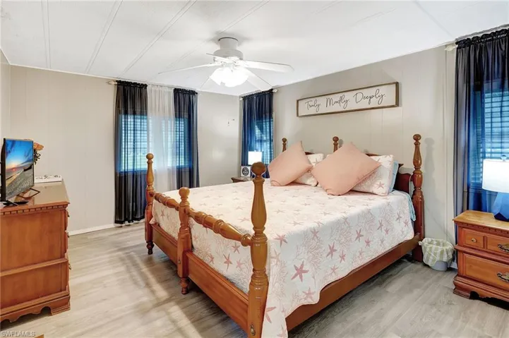 Bedroom with multiple windows, ceiling fan, light hardwood / wood-style flooring, and wood walls