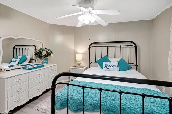 Bedroom featuring ceiling fan, wooden walls, and light hardwood / wood-style flooring