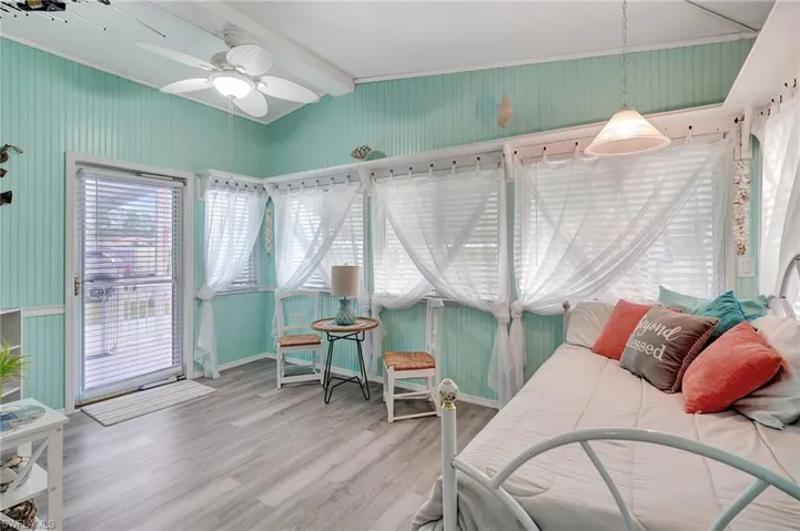 Bedroom with hardwood / wood-style floors, lofted ceiling with beams, crown molding, ceiling fan, and access to exterior