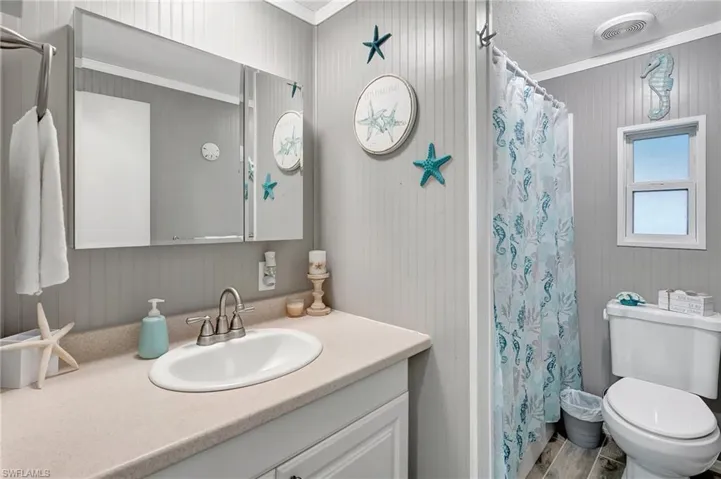 Bathroom featuring vanity, hardwood / wood-style floors, a textured ceiling, and ornamental molding
