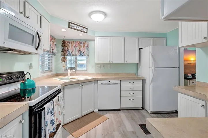 Kitchen featuring white cabinets, white appliances, light hardwood / wood-style floors, and sink