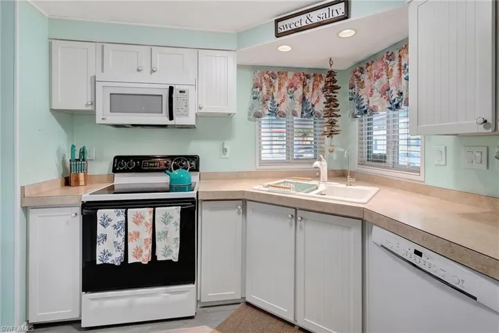 Kitchen with white cabinets, white appliances, and sink