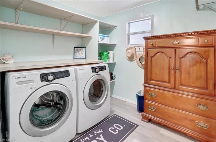Clothes washing area with washer and dryer, light hardwood / wood-style floors, and wood walls