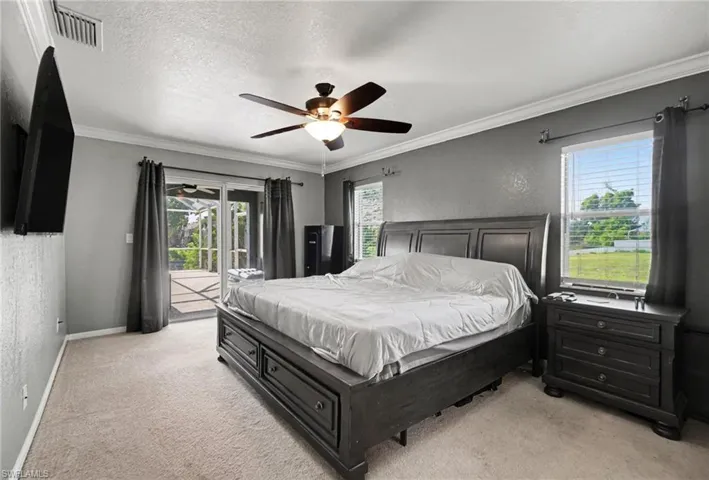 Spacious room featuring light-colored carpet, a ceiling fan with integrated lighting, and crown molding