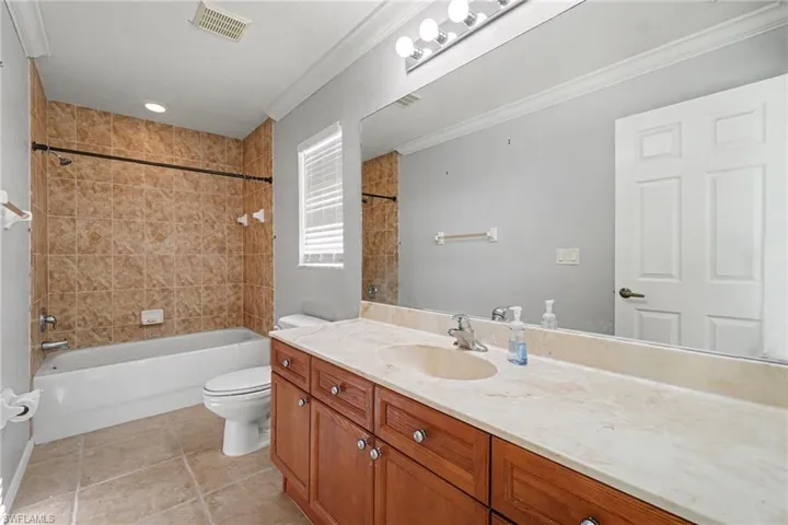 Bathroom featuring a vanity with wood-finish cabinetry, a light-colored countertop, and a spacious mirror