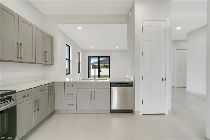 Kitchen with gray cabinets, stainless steel appliances, kitchen peninsula, and sink
