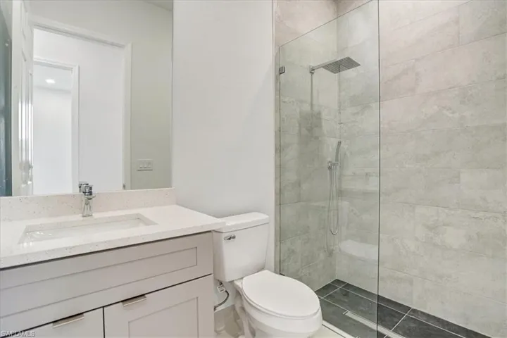 Guess Bathroom featuring toilet, a tile shower, and vanity