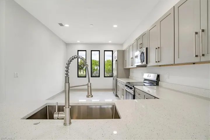 Kitchen with light stone countertops, stainless steel appliances, and sink