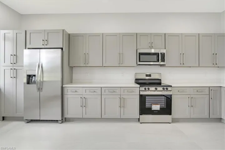 Kitchen with appliances with stainless steel finishes and gray cabinetry