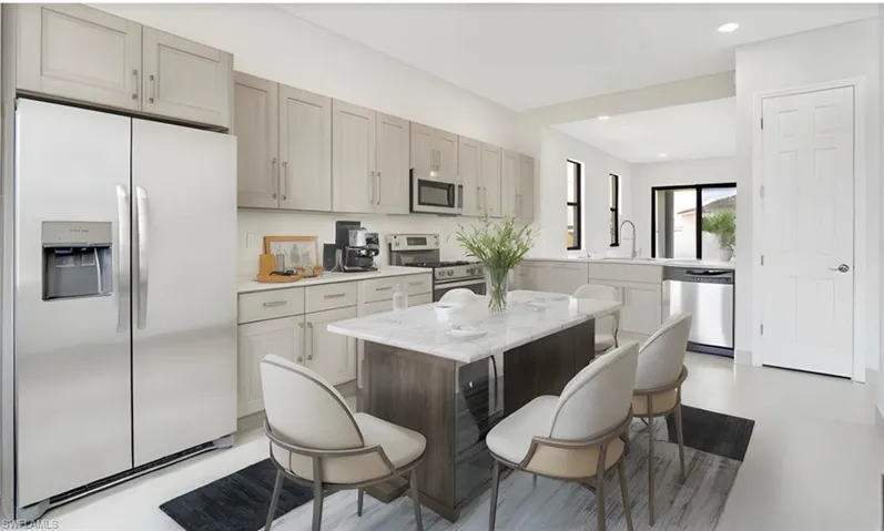 Kitchen featuring appliances with stainless steel finishes, a breakfast bar area, a center island, and light stone counters