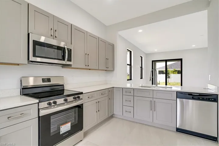Kitchen with gray cabinetry, sink, and appliances with stainless steel finishes