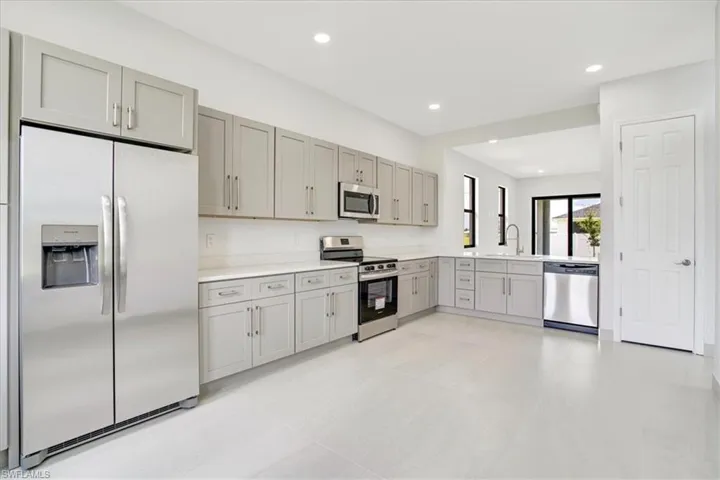 Kitchen with appliances with stainless steel finishes, gray cabinetry, and kitchen peninsula