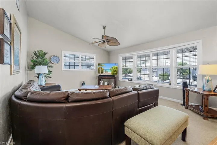 Living area featuring lofted ceiling, carpet flooring, and a ceiling fan