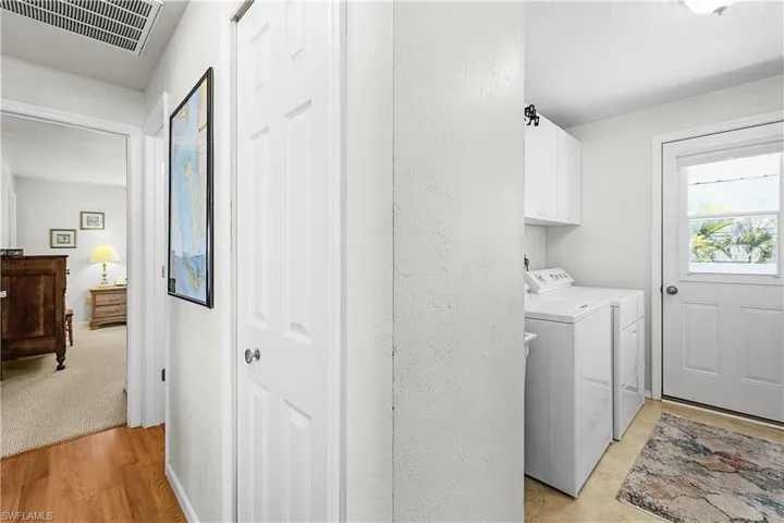 Laundry area with light wood-type flooring, washer and clothes dryer, and cabinet space