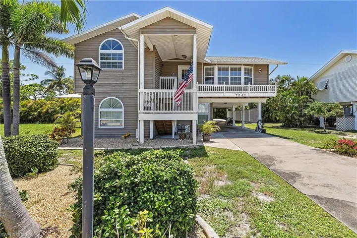 Coastal inspired home with a carport, driveway, and a porch