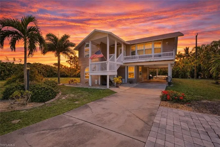 Beach home with driveway, a lawn, a carport, and a porch
