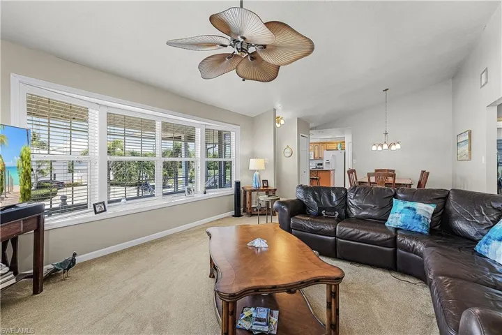 Living room with lofted ceiling, light carpet, and a ceiling fan