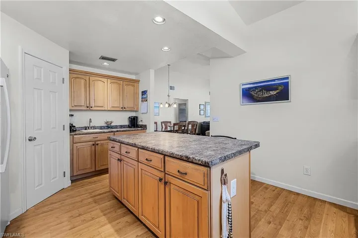 Kitchen featuring light wood-style flooring, hanging light fixtures, recessed lighting, a center island, and white fridge