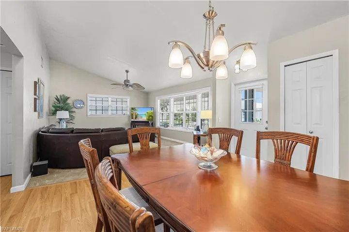 Dining room featuring light wood-style floors, vaulted ceiling, ceiling fan, and a chandelier