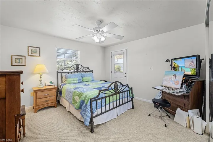 Bedroom featuring multiple windows, light carpet, a textured ceiling, and a ceiling fan