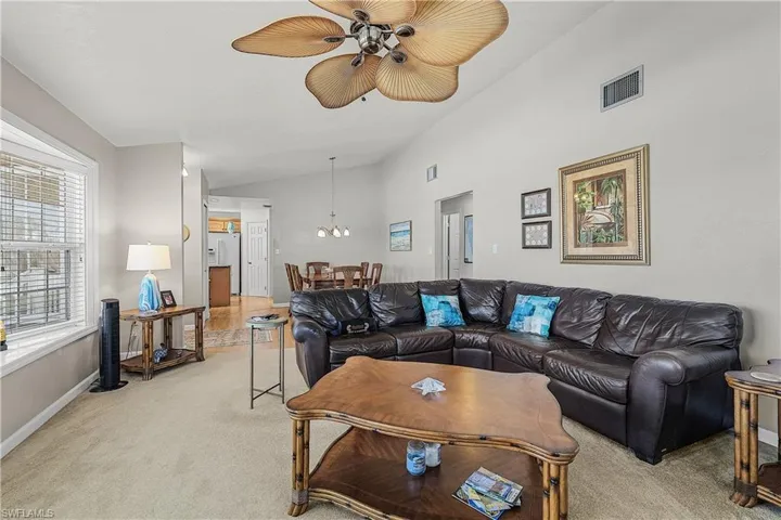 Living room featuring light carpet and a ceiling fan
