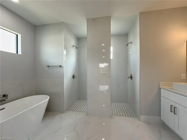 Full bath with vanity, a freestanding bath, marble finish floor, and a marble finish shower