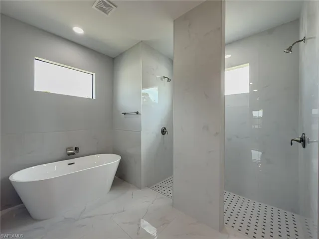 Full bath with marble finish floor, a marble finish shower, visible vents, and a soaking tub