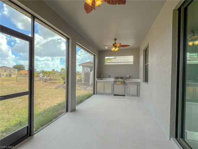 Unfurnished sunroom featuring ceiling fan, an outdoor kitchen, and a sink