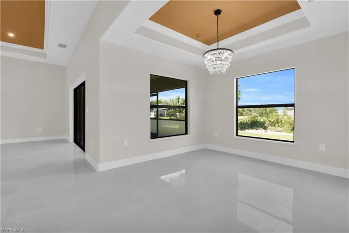Unfurnished room with a tray ceiling and a chandelier