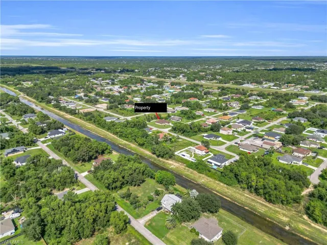 Aerial view of property's location featuring nearby suburban area and a tree filled landscape