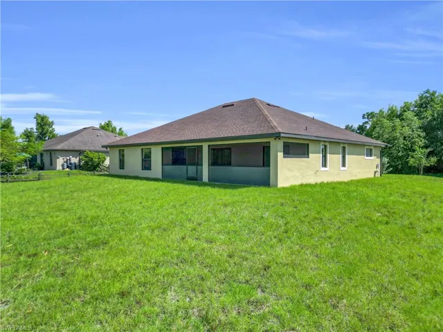 Back of property with stucco siding and a lawn