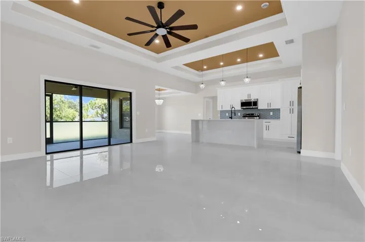 Unfurnished living room with a raised ceiling, a ceiling fan, and ornamental molding