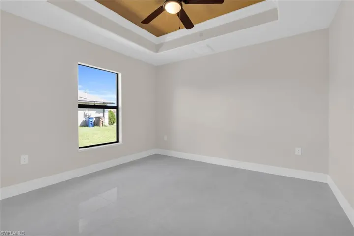 Spare room with a tray ceiling, crown molding, ceiling fan, and tile patterned flooring