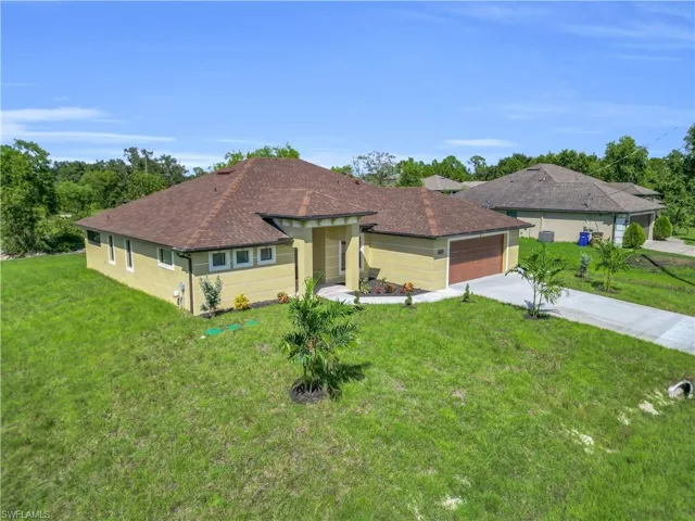 View of front of property with a front yard, concrete driveway, a garage, and stucco siding