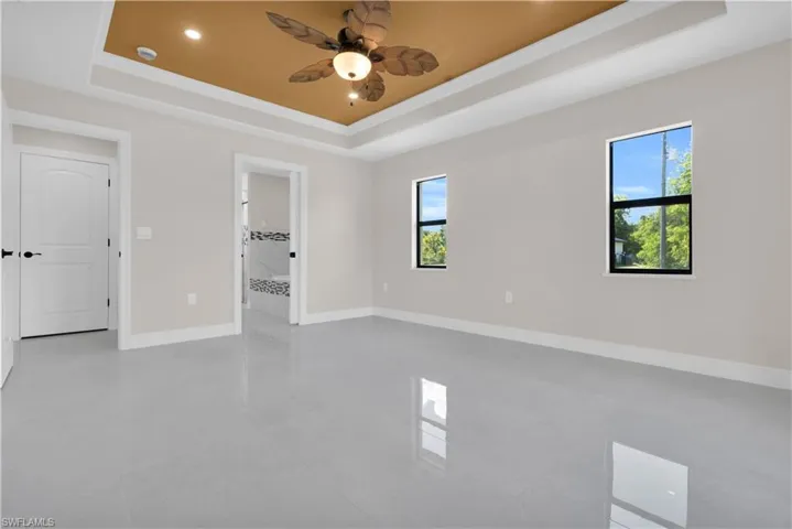 Spare room featuring a tray ceiling, a ceiling fan, recessed lighting, and light tile patterned flooring