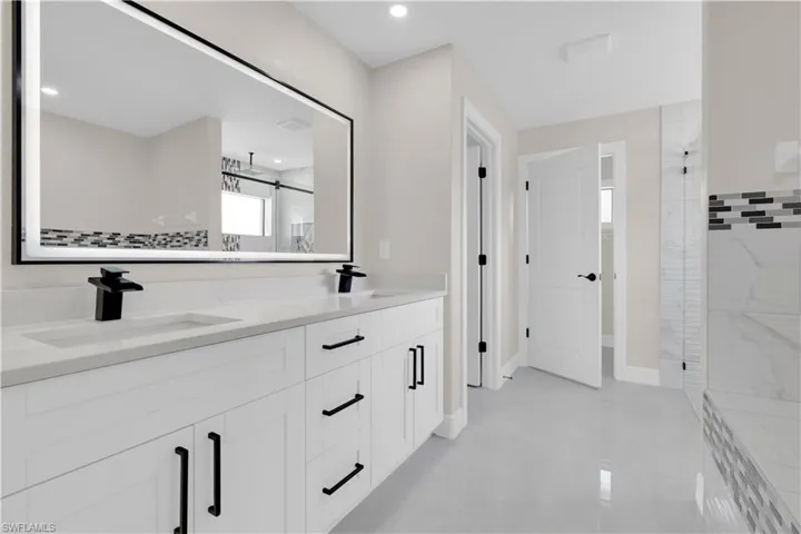 Bathroom with a shower stall, double vanity, light tile patterned flooring, and recessed lighting
