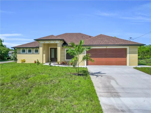Prairie-style home featuring roof with shingles, concrete driveway, a front yard, stucco siding, and a garage