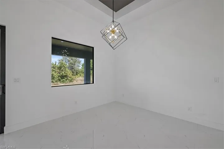 Spare room featuring marble finish flooring and a chandelier