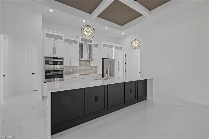 Kitchen featuring glass insert cabinets, coffered ceiling, light stone countertops, backsplash, and pendant lighting