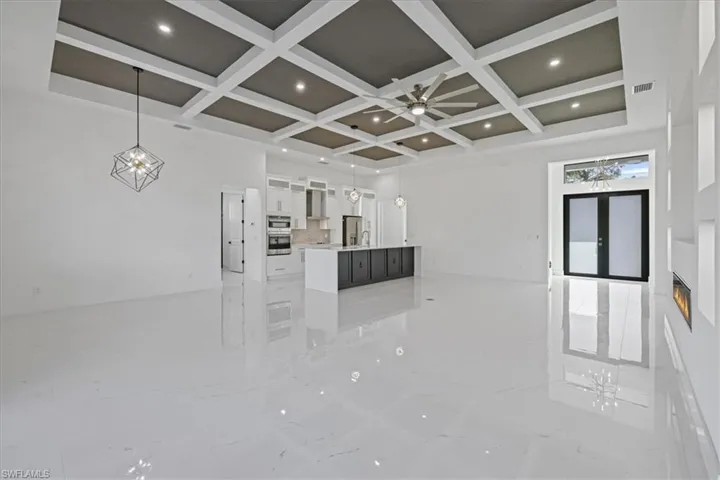 Unfurnished living room featuring recessed lighting, light marble finish floors, coffered ceiling, and ceiling fan