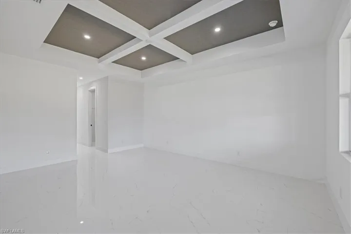 Spare room with coffered ceiling, recessed lighting, and light marble finish flooring
