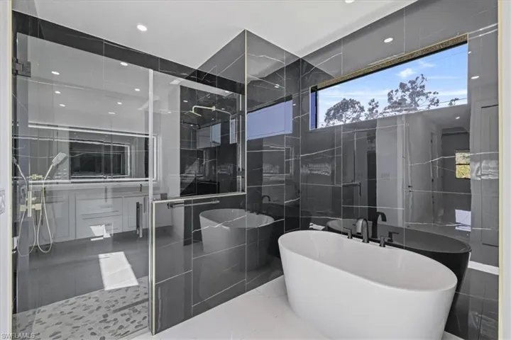 Bathroom with tile walls, a shower stall, a soaking tub, recessed lighting, and marble tiled floors