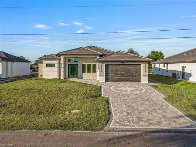 Prairie-style house featuring a front yard, stucco siding, decorative driveway, and an attached garage