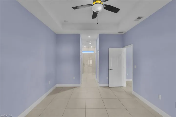 Spare room featuring a tray ceiling, ceiling fan, and light tile patterned flooring