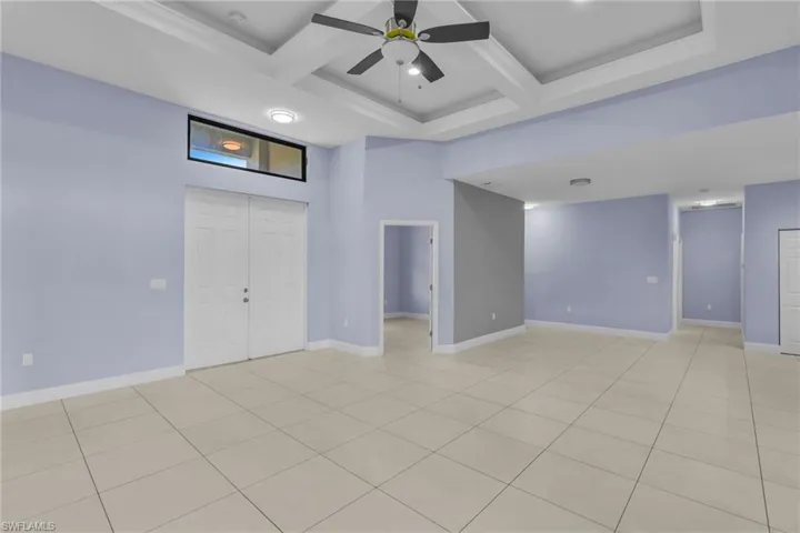 Tiled spare room featuring beamed ceiling, ceiling fan, and coffered ceiling
