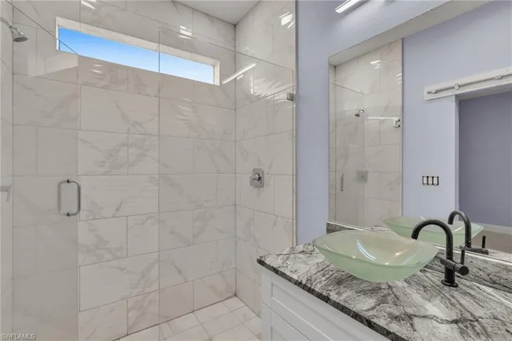 Bathroom with tile patterned flooring, vanity, and a shower with door