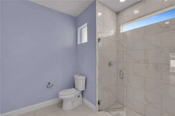 Bathroom with tile patterned flooring, an enclosed shower, and toilet